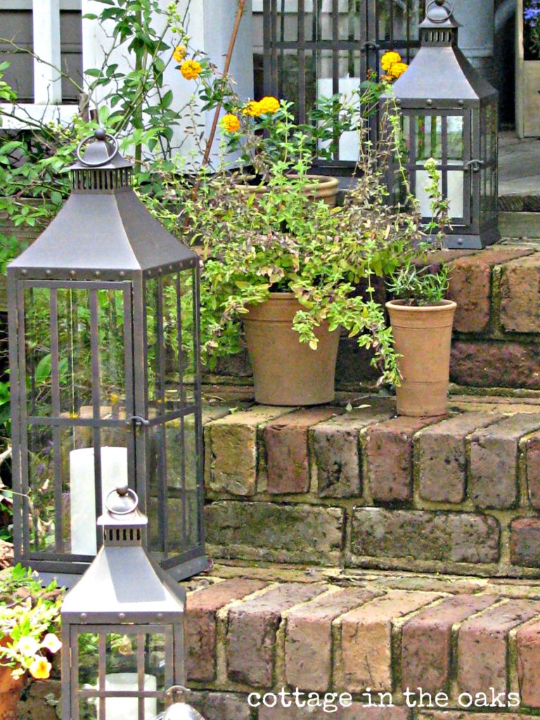 Summer Front Porch Decor in Cottage Style with Large Metallic Lanterns and Terracotta Planters